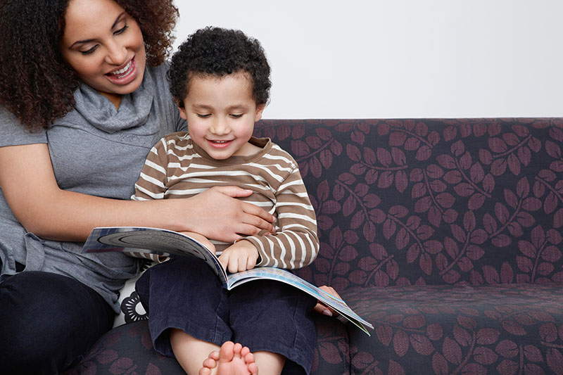 Woman reading to a child on the couch