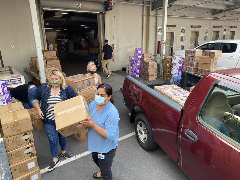 Staff stacking boxes in and around a store room during a delivery