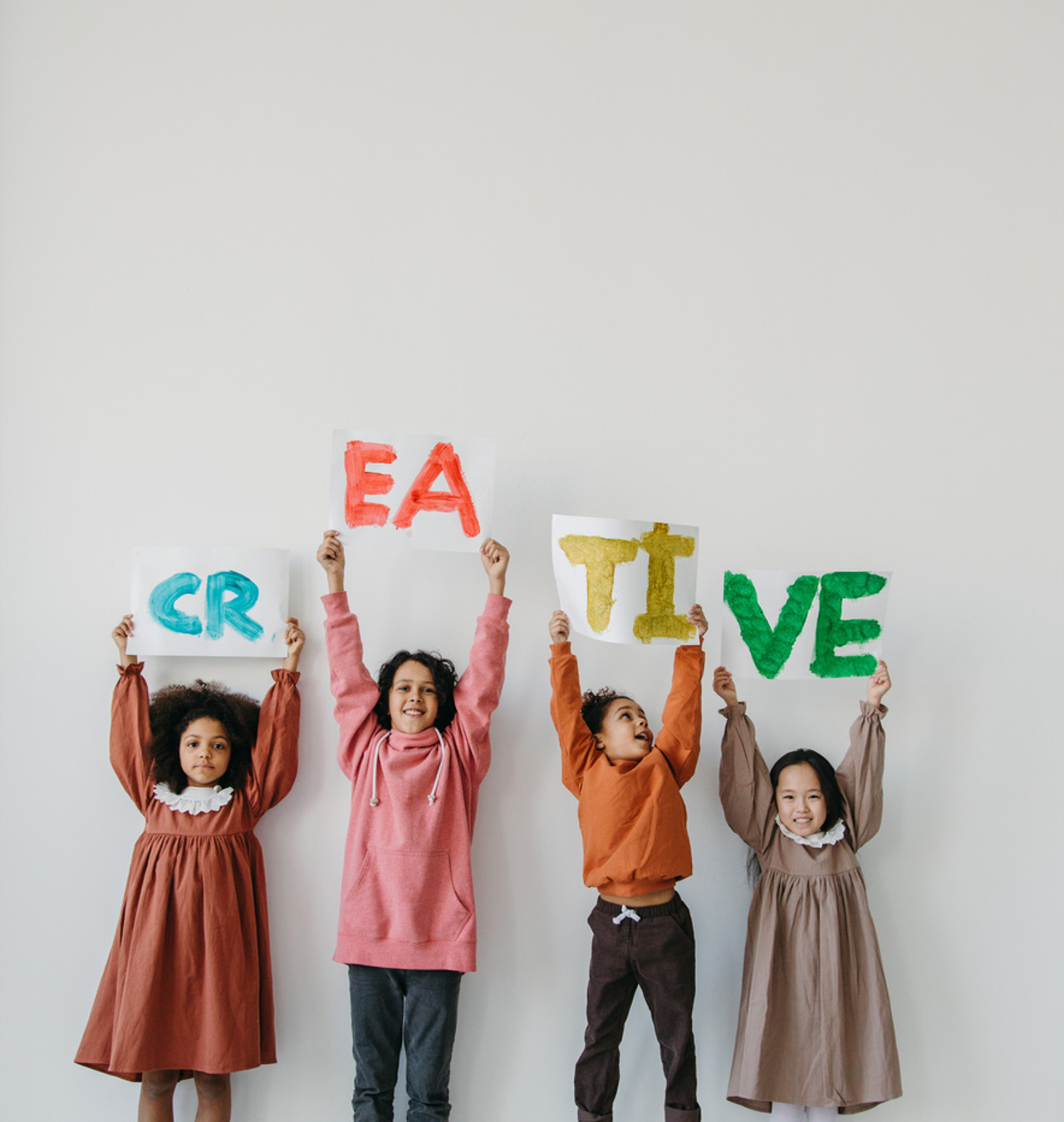 Kids Holding Up a Painted Sign that Says 'Creative'